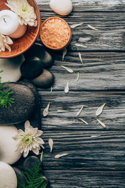 flat lay with spa and massage treatment arrangement with pebbles, salt and chrysanthemum flowers on wooden background