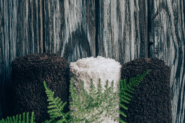 flat lay with towels and fern plant for spa on wooden background