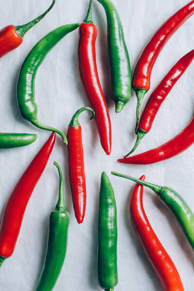 elevated view of red and green chili peppers on white surface