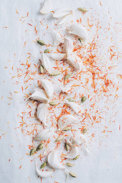 elevated view of scattered garlic and spices on white table