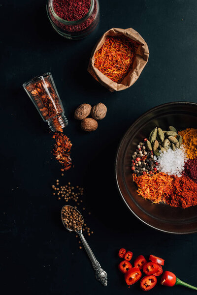 top view of spices in plate, jars and spoon on table