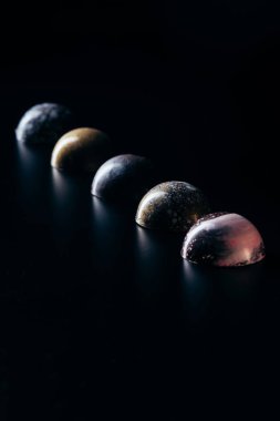 chocolate candies placed in row on black background  clipart