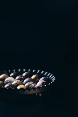 siyah arka plan üzerine kabın içinde farklı çikolata şekerleme yığını görüntüsünü kapatmak 