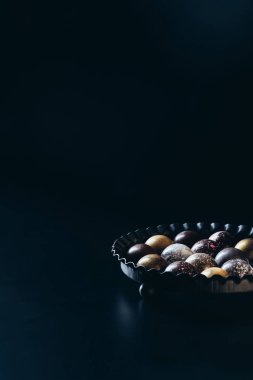 siyah arka plan üzerine kabın içinde çeşitli çikolata şekerleme yığını