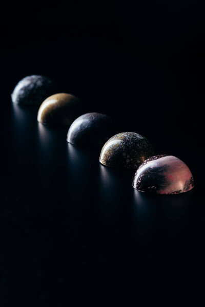 chocolate candies placed in row on black background 