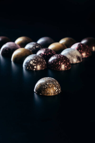 closeup view of pile of chocolate candies on black background 