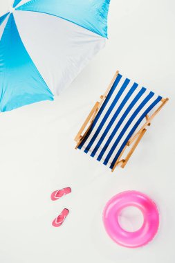 top view of beach umbrella, striped beach chair, flip flops and inflatable ring isolated on white clipart