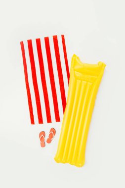 çizgili plaj havlusu, flip flop ve şişme yatak üzerinde beyaz izole üstten görünüm