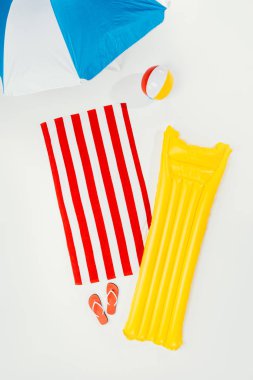 plaj şemsiyesi, havlu, flip flop, şişme top ve yüzme yatağı üzerinde beyaz izole üstten görünüm