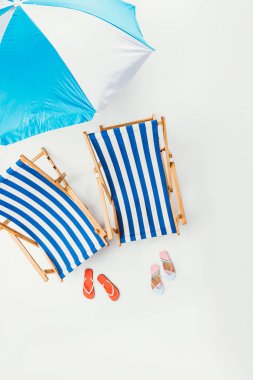 plaj şemsiyesi, çizgili plaj sandalyeleri ve flip flop üzerinde beyaz izole üstten görünüm