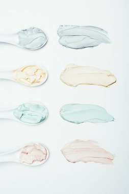kaşık ve beyaz yüzey üzerinde izole satır yerleştirilen renkli kil maskesi lekeler üstten görünüm 