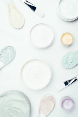 kapsayıcılar, kaşık ve beyaz yüzey üzerinde izole fırçalar çeşitli kil maskeleriyle düz lay 
