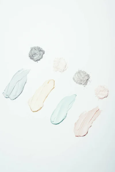 top view of various clay powder and colorful clay mask smudges placed in row isolated on white surface