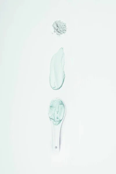 flat lay with clay powder, smudge and spoon with clay mask isolated on white surface