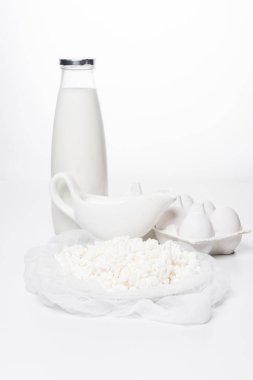 close-up shot of milk, homemade cottage cheese and eggs in carton on white surface clipart