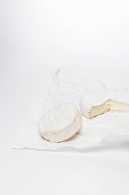 close-up shot of brie cheese on crumpled paper and on white surface clipart