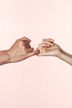 cropped image of woman and man crossing little fingers isolated on pink background clipart