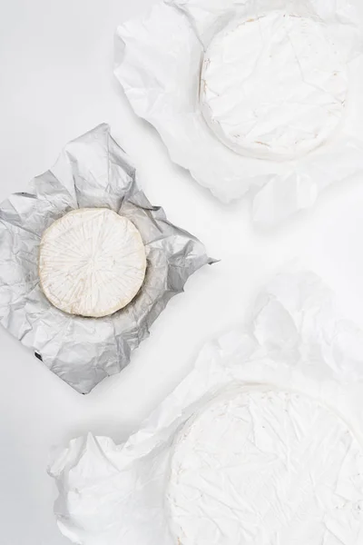 top view of brie cheese heads on crumpled paper and on white tabletop