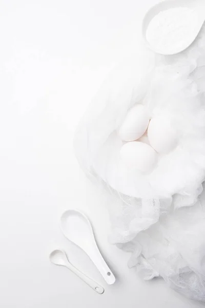 白い表面にサワー クリームをスプーンで寒冷紗で生の鶏肉卵の上から見る  — 無料ストックフォト