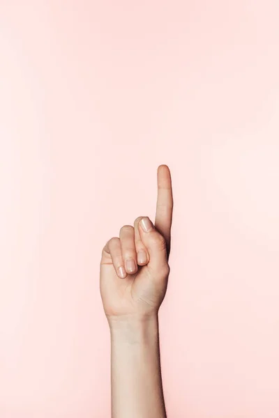 女性在粉红色背景下做手指凸起手势的裁剪图像 — 图库照片