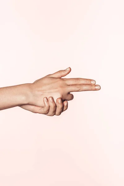 ピンクの背景に分離された銃の形で形づけられる女性の手のトリミングされた画像 — ストック写真