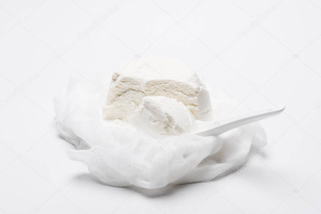 delicious cottage cheese on cheesecloth with spoon on white surface