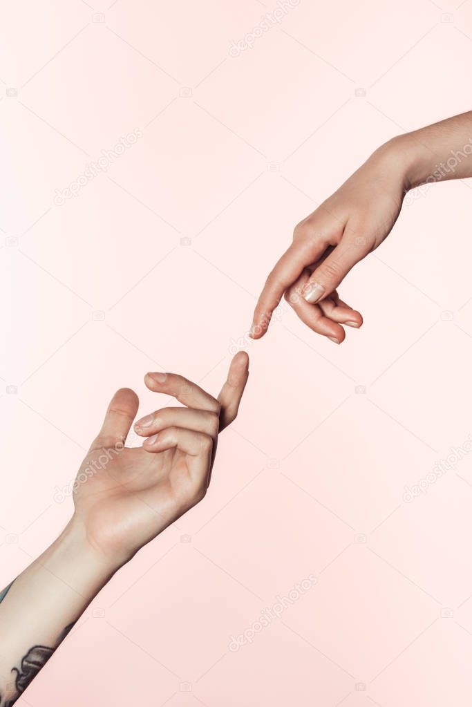 cropped shot of tattooed man and woman approaching to each other by fingers isolated on pink background