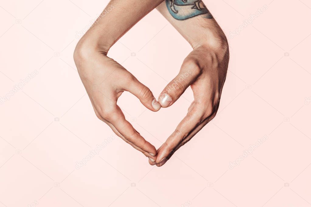 cropped shot of woman and tattooed man doing heart symbol by hands isolated on pink background 