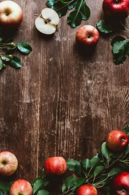 flat lay with arranged ripe apples and green leaves on wooden tabletop clipart