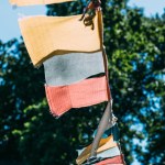 Close up of garland with colorful flags outdoors with trees on background