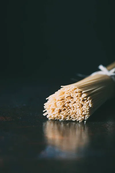 Widok Zbliżenie Spaghetti Zapakowane Przez Wstążki Czarnym Tle — Zdjęcie stockowe