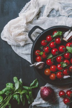 ahşap zemin üzerine gazlı bez üzerinde tavada üstten görünüm kiraz domates, sarımsak ve fesleğen yaprakları