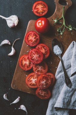 kesme tahtası üzerinde kırmızı organik domates, sarımsak ve tuz kaşık üstten görünüm