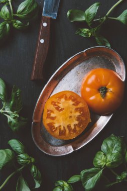 sarı organik domates bıçağı ve fesleğen ile metal plaka üzerinde yukarıdan bırakır