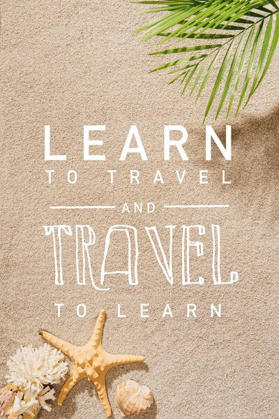 top view of palm branch over sandy beach with "learn to travel and travel to learn" lettering