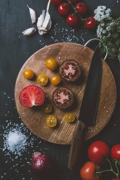 Top view of black prince tomatoes and yellow cherry tomatoes on cutting board with knife, garlic and salt — Stock Image Top View Black Prince Tomatoes Yellow Cherry Tomatoes Cutting Board Royalty Free Stock Images