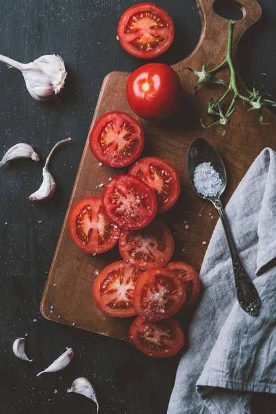 Top view of red organic tomatoes, garlic and salt in spoon on cutting board — Stock Image Top View Red Organic Tomatoes Garlic Salt Spoon Cutting Board Stock Photo