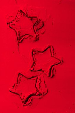 elevated view of shapes of cookie cutters in shape of stars on red powder  clipart