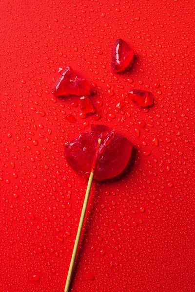 Bovenaanzicht Van Gebroken Lollipop Rode Ondergrond Met Water Druppels — Stockfoto