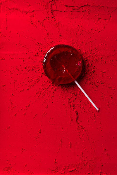 вид сверху на красный леденец на красном порошке
