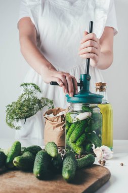 cropped image of woman preparing preserved cucumbers at kitchen clipart