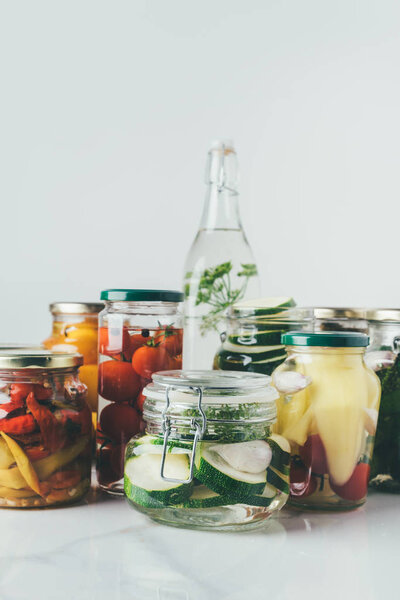 glass jars with preserved vegetables on table in kitchen