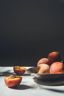 food composition with ripe peaches in metal bowl on black backdrop clipart