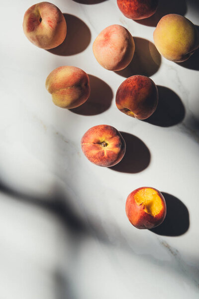 flat lay with ripe peaches on light marble tabletop with shadows