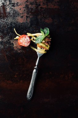 nane ile makarna tarafından sarılmış çatal yükseltilmiş görünümünü bırakır, jamon ve kiraz domates rendelenmiş parmesan tablo/EC