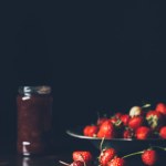 Selective focus of strawberries in silver tray and fruit jam in jar on black