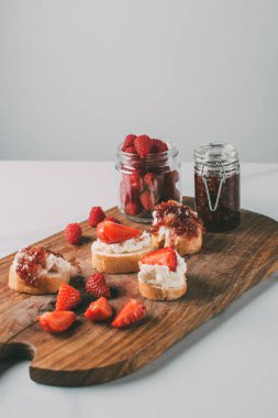 çilek reçeli kavanozlara ile kesme tahtası ve krem peynirli sandviç kadar kapatın ve gri jam 
