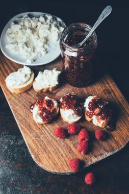 yüksek açı ahududu görünümünü, kavanoz reçel, sandviç ve krem peynir kesme tahtası üzerinde plaka üzerinde 