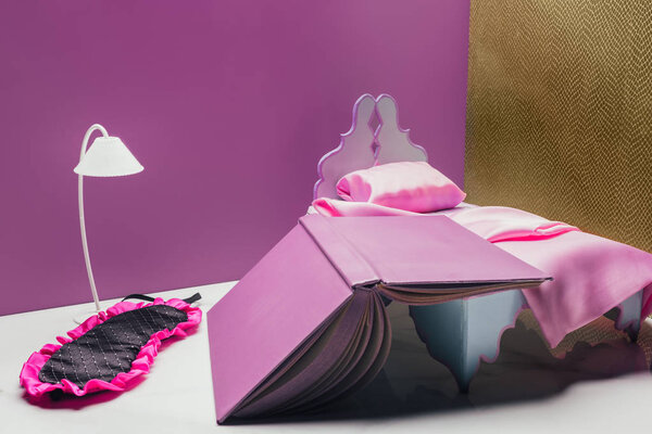 игрушечная кровать с маской и книгой в миниатюре
