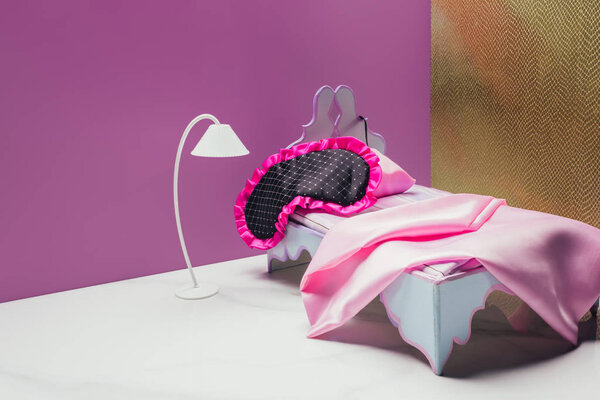 игрушечная кровать и факел с маской реального размера в миниатюрной комнате
